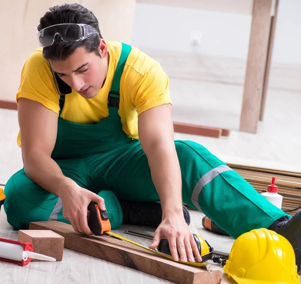 Empreiteiro que trabalha no piso de madeira laminado — Fotografia de Stock