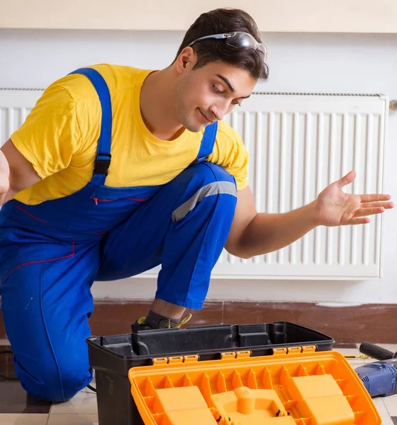Jonge reparateur die verwarmingspaneel repareert — Stockfoto