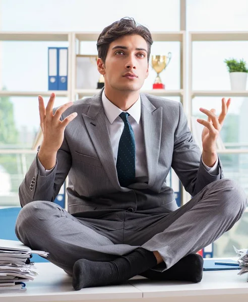 Businessman sitting on top of desk in office — Stock Photo, Image