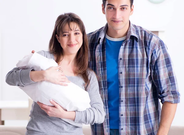 Fiatal szülők újszülött kisbabával az ágy mellett — Stock Fotó
