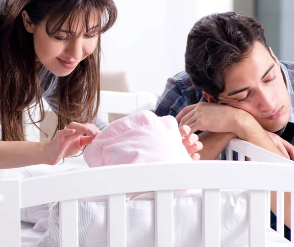 Young parents with their newborn baby near bed cot — Stock Photo, Image