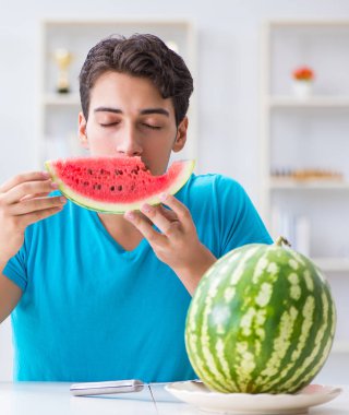 Evde karpuz yiyen bir adam.