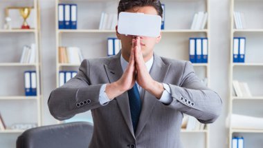 Sanal gerçeklikteki iş adamı VR gözlükleri masanın üstünde meditasyon yapıyor.