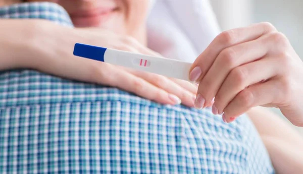 Vrouw en echtgenoot kijken naar zwangerschapstest — Stockfoto