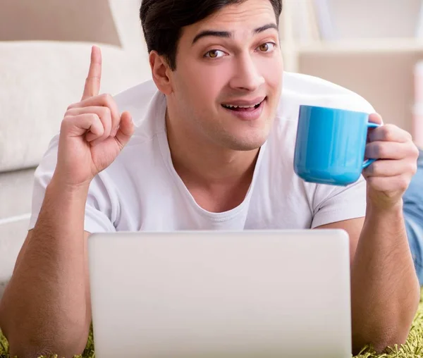 Man working on laptop at home on carpet floor — Stock Photo, Image