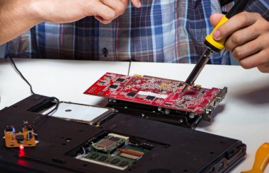 Genç tamirci ana yaban domuzunun elektrik parçalarını lehimliyor.