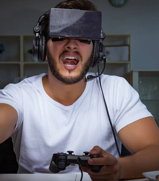 Jovem jogando jogos longas horas atrasado no escritório — Fotografia de Stock