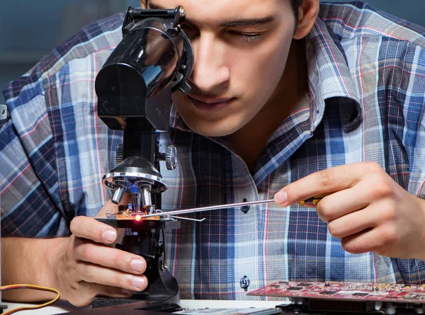 Ремонтник пытается починить ноутбук с помощью микроскопа — стоковое фото