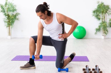 Genç yakışıklı adam içeride spor yapıyor.