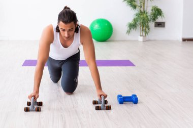Genç yakışıklı adam içeride spor yapıyor.