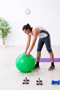 Genç yakışıklı adam içeride spor yapıyor.