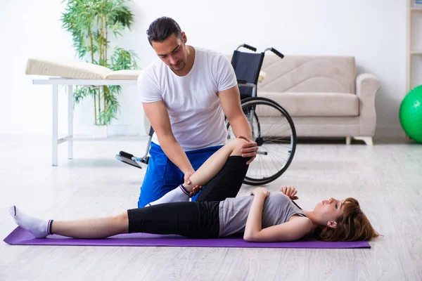 Fisioterapeuta masculino haciendo ejercicios con una mujer lesionada en el suelo —  Fotos de Stock