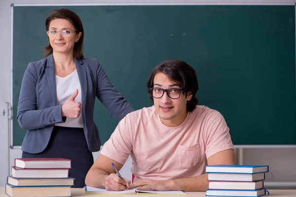 Old female teacher and male student in the classroom — Stock Photo, Image