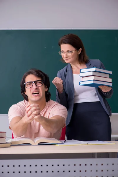 Oude vrouwelijke leraar en mannelijke student in de klas — Stockfoto