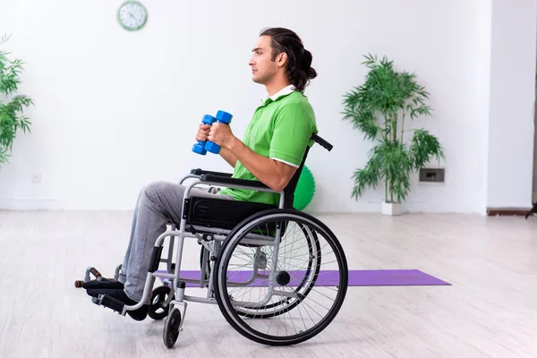 Jovem em cadeira de rodas fazendo exercícios dentro de casa — Fotografia de Stock