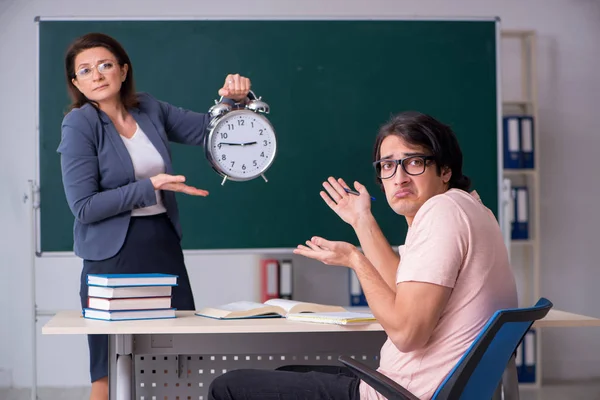 Old female teacher and male student in the classroom