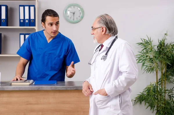 Dwóch lekarzy rozmawiających w recepcji w szpitalu. — Zdjęcie stockowe