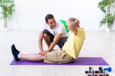 Yaşlı adam içeride egzersiz yapıyor.