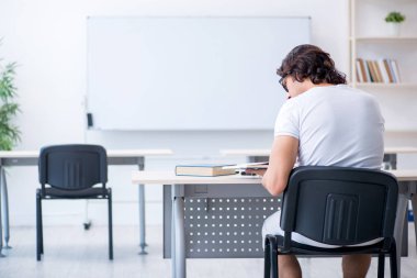 Beyaz tahtanın önünde genç bir erkek öğrenci.