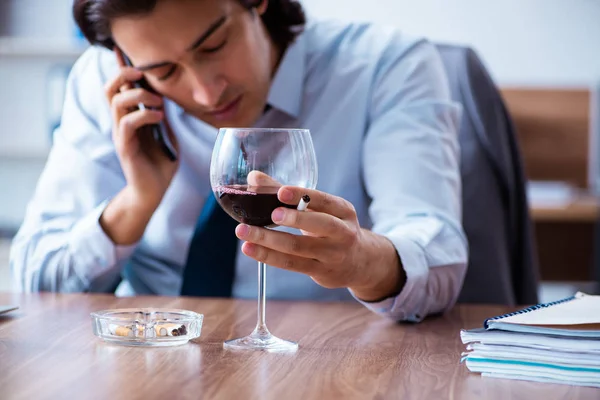 Male employee drinking alcohol and smoking cigarettes at workpla — Stock Photo, Image