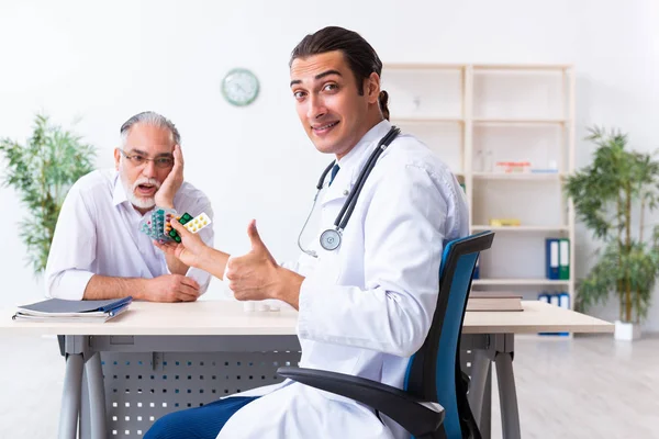 Homem velho visitando jovem médico masculino — Fotografia de Stock