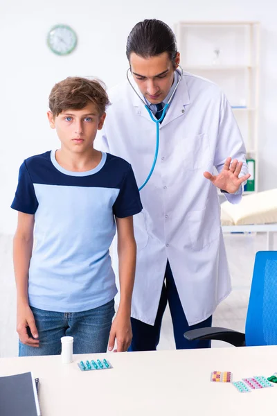 Jeune homme médecin examinant garçon à la clinique — Photo