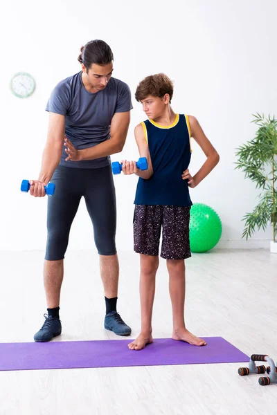 Jovem pai e seu filho fazendo exercícios — Fotografia de Stock