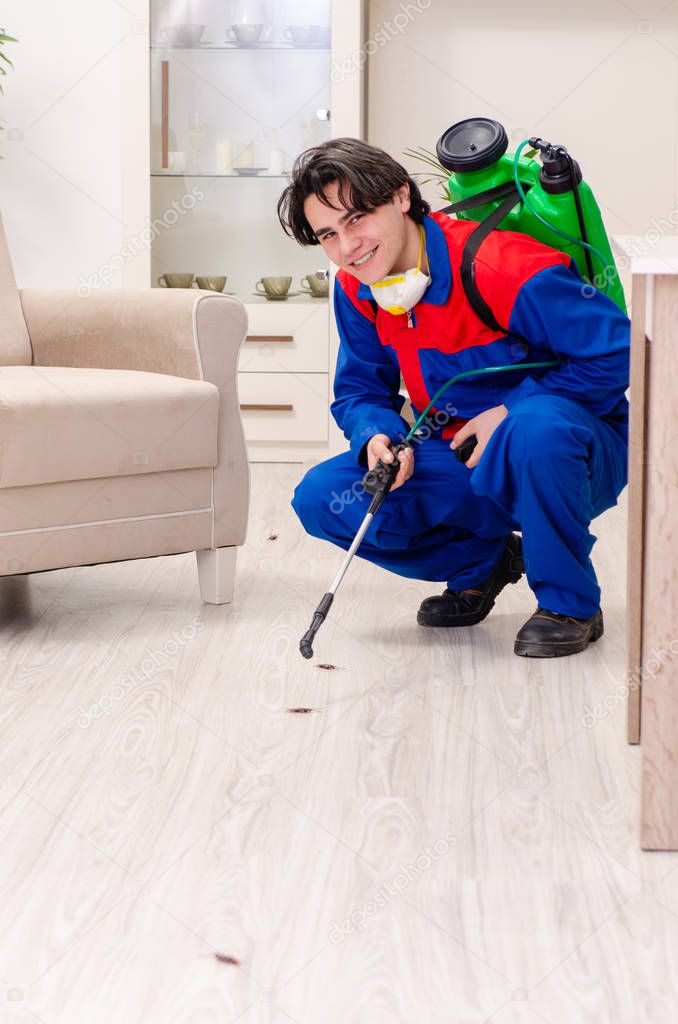 Young contractor doing pest control at home