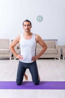 Genç adam evde antrenman ve egzersiz yapıyor.