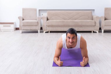 Genç adam evde antrenman ve egzersiz yapıyor.