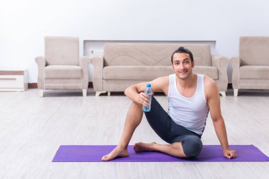 Genç adam evde antrenman ve egzersiz yapıyor.