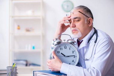 Klinikte çalışan yaşlı erkek doktor.