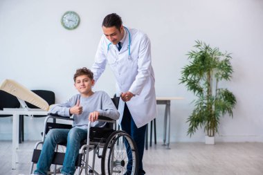 Genç erkek doktor pediatrist ve tekerlekli sandalyedeki çocuk.