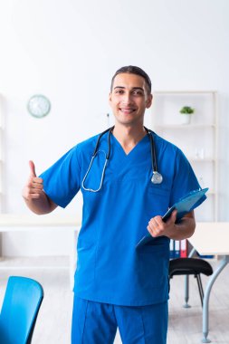 Klinikte çalışan genç erkek doktor.