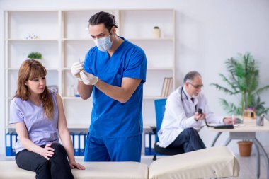 İki doktor genç kadını muayene ediyor.