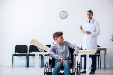 Genç erkek doktor pediatrist ve tekerlekli sandalyedeki çocuk.