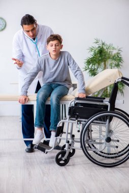Genç erkek doktor pediatrist ve tekerlekli sandalyedeki çocuk.