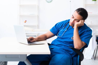 Klinikte çalışan genç erkek doktor.