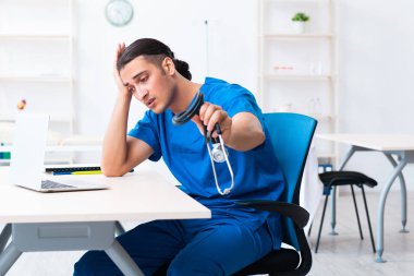 Klinikte çalışan genç erkek doktor.