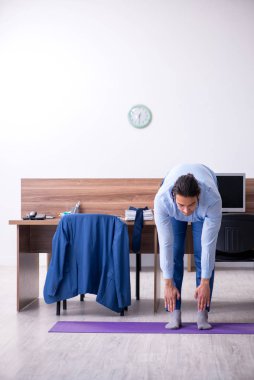 Genç yakışıklı işadamı iş yerinde egzersiz yapıyor.