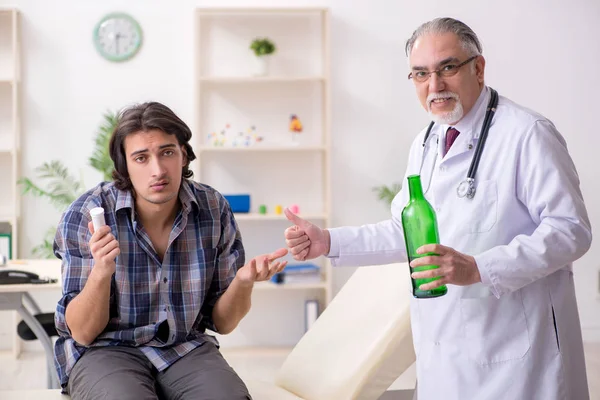 Молодой алкоголик посещает старого врача — стоковое фото
