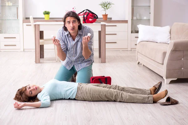 Casal jovem no conceito de primeiros socorros em casa — Fotografia de Stock