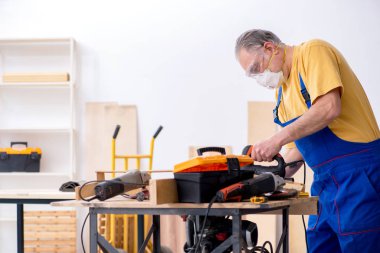 Yaşlı erkek marangoz atölyede çalışıyor.