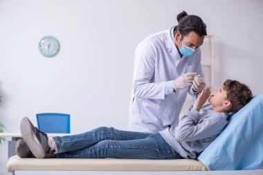 Genç çocuk hastanede doktoru ziyaret ediyor.