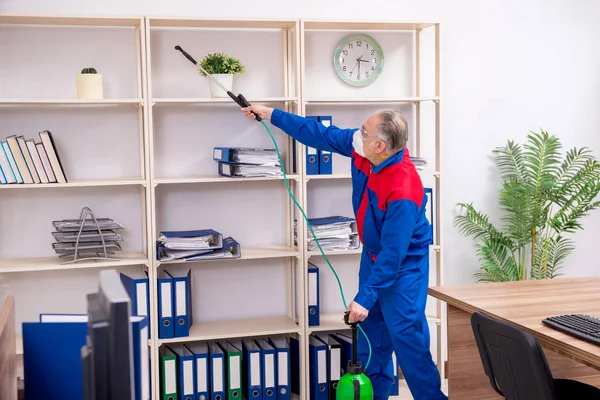 Velho empreiteiro profissional fazendo controle de pragas no escritório — Fotografia de Stock
