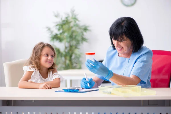 Little girl visiting old female doctor — Stock Photo, Image