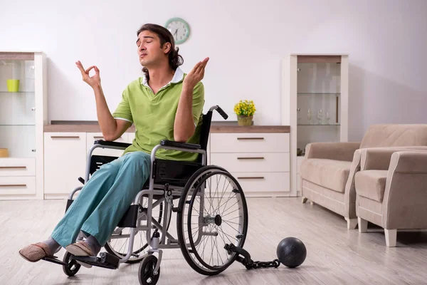 Jeune homme invalide en fauteuil roulant souffrant à la maison — Photo