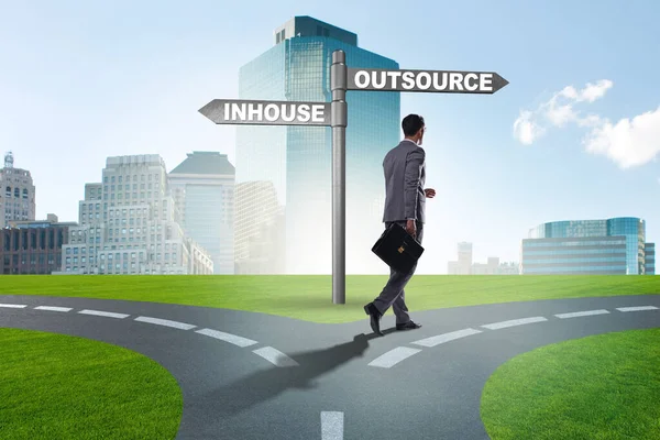 Businessman at crossroads deciding between outsourcing and inhou — Stock Photo, Image