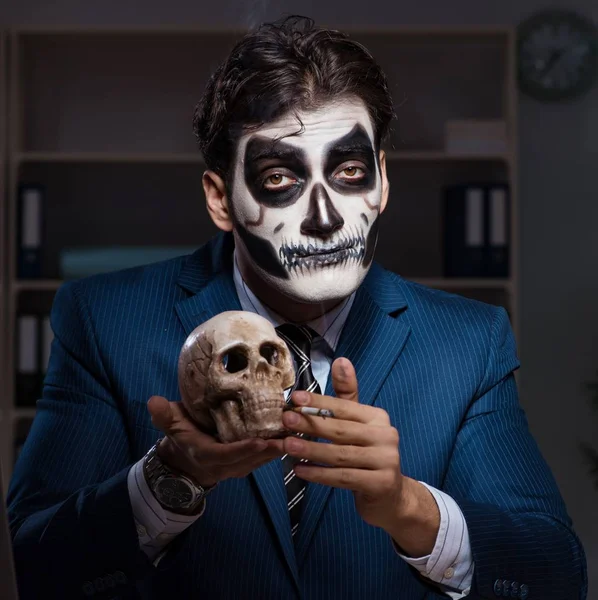 O homem de negócios com máscara facial assustadora trabalhando até tarde no escritório — Fotografia de Stock
