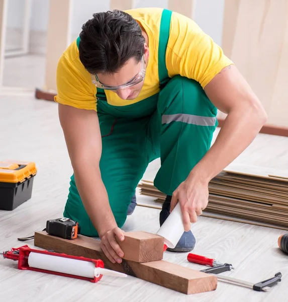 Empreiteiro que trabalha no piso de madeira laminado — Fotografia de Stock